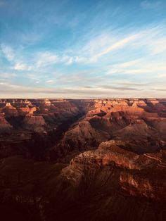 the sun is setting at the edge of the grand canyon, with blue skies above