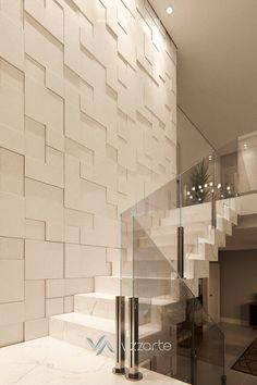 a staircase with glass railings and white tiles on the wall in a modern home