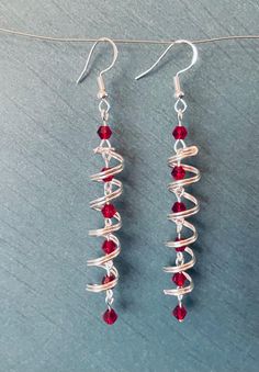 the earrings are made with silver wire and red glass beads