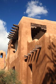 an adobe - style building with several windows on the front and side, against a cloudy sky