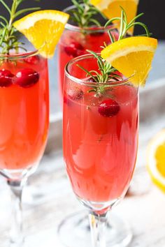 two glasses filled with red wine and garnished with lemons, rosemary and cranberries