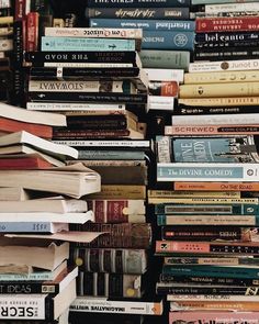 a pile of books stacked on top of each other in front of a wall full of them