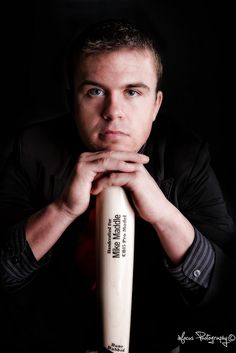 a man is holding a baseball bat in his hands and posing for the camera with his arms crossed