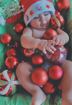 a baby is laying down surrounded by christmas ornaments