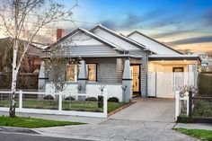 a house with white picket fence and trees