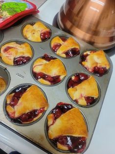 a muffin tin filled with mini pies sitting on top of a stove