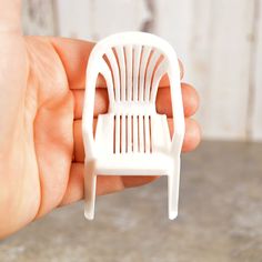 a miniature white plastic chair sitting in someone's hand