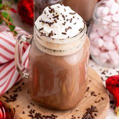 a hot chocolate drink with whipped cream and sprinkles in a mason jar