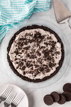 an oreo cookie crust pie on a plate with chocolate cookies and forks next to it