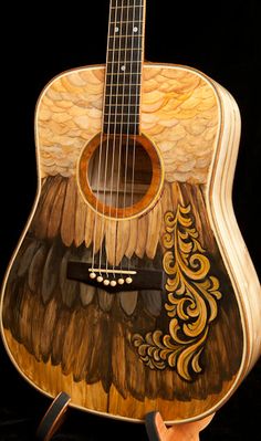 a wooden guitar with an intricate design on the back and sides, hanging from a black background