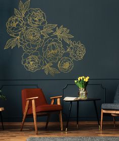 two chairs and a table in front of a wall with flowers on it