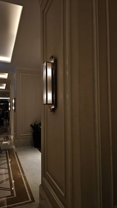 an open door leading into a hallway with lights on the ceiling and floor tiles on the walls