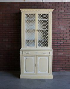 a white china cabinet sitting next to a brick wall