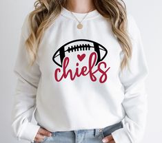 a woman wearing a sweatshirt that says chiefs with a football on the front and heart in the middle