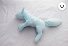 a blue stuffed animal laying on top of a white sheet