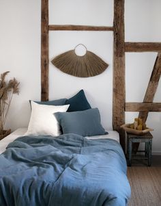 a bed with blue sheets and pillows in front of an old wooden headboard that has been made into a wall decoration