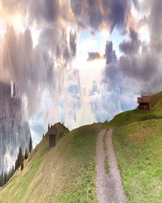 a bench on top of a grassy hill with clouds in the sky over it and a dirt path leading to a small cabin