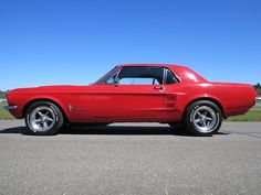 a red mustang sitting on top of a parking lot