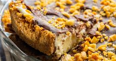 a close up of a piece of cake in a glass dish with chocolate and nuts on top