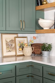 a kitchen with green cabinets and pictures on the counter top in front of shelves filled with books