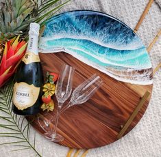 a bottle of champagne and two wine glasses on a wooden tray with pineapples