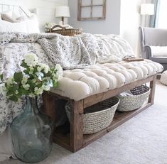 a bed with pillows, blankets and baskets on the bottom shelf in front of it