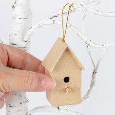 a hand holding a small wooden birdhouse ornament