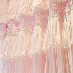 there are many pink dresses hanging on the rack in front of each other with white lace trims