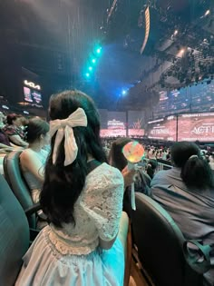 a woman in a white dress is holding a fan at a convention or show hall