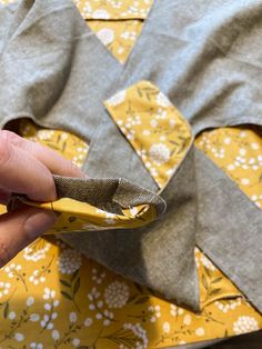 someone is cutting fabric on top of a yellow flowered shirt