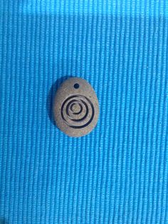 a button that is sitting on the side of a blue cloth covered tablecloth with an image of a spiral in it