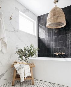 a bathroom with black and white tiles, a wooden stool and a basket hanging from the ceiling