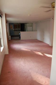 an empty living room with pink carpeting and no one in the house or furniture