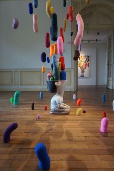 an art installation with various colored objects floating in the air and on top of wood flooring