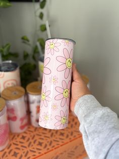 a person holding a pink cup with flowers on it