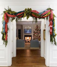 a living room decorated for christmas with red, green and blue ribbons hanging from the ceiling