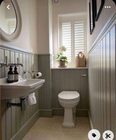 a white toilet sitting in a bathroom next to a sink and window with shutters