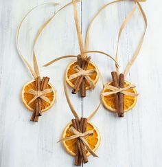 an orange cut in half with cinnamon sticks tied around it on a white wooden table