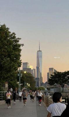 many people are walking on the sidewalk in front of some tall buildings and skyscrapers