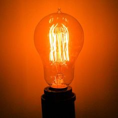 a light bulb sitting on top of a wooden stand in front of a yellow wall