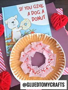 a paper plate with a donut on it next to a book and yarn balls