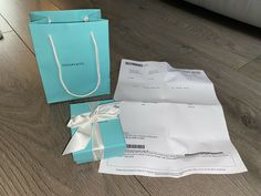 two blue shopping bags sitting on top of a wooden floor next to some paper packages