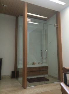 a bathroom with a walk in shower next to a wooden bench and rug on the floor