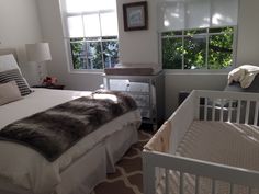 a baby's room with a crib, dresser and window