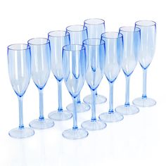 a group of blue wine glasses lined up on a white surface with one empty glass in the middle