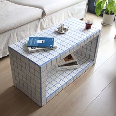 a blue and white table with books on it in the middle of a living room