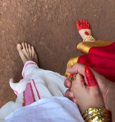 a woman in red and gold is holding onto a baby's foot with her hands