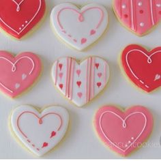 heart shaped cookies are arranged in the shape of hearts on a white tablecloth with pink and red icing