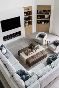 a living room with couches, tables and a television mounted on the wall above it