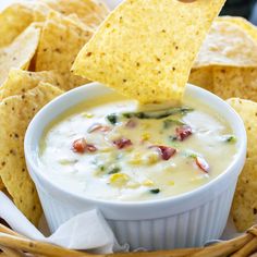 a tortilla chip being dipped into a bowl of quesadilla dip